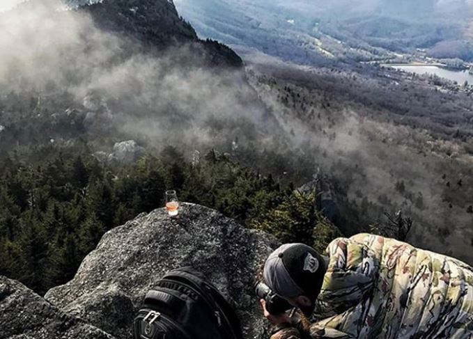 Instagram influencer Whisky with a View (Nathan Woodruff) takes a photo from a mountain summit. 