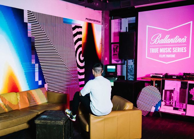 Felipe Pantone examining art piece with Ballantines logo